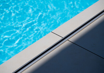 Coverseal-landscape3 Détail du rail de la Coverseal au bord de la piscine, parfaitement intégré dans le carrelage clair de la terrasse.