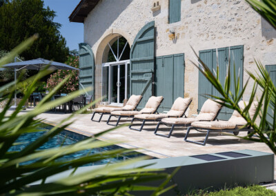 Sequoia6 Vue latérale de la terrasse avec transats alignés au bord de la piscine, équipée d’une Coverseal grise discrète et moderne.