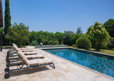 Sequoia9 Perspective du bord opposé de la terrasse, montrant la piscine bleue entourée de transats et intégrée dans un environnement verdoyant.